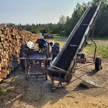conveyor belt outside beside a large pile of cut logs