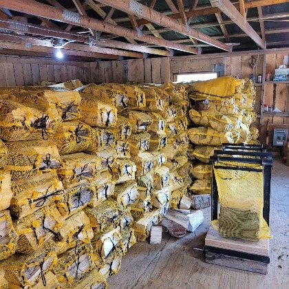 a large pile of cut logs wrapped in individual yellow mesh bags